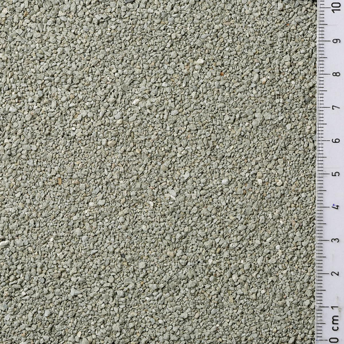 Close-up of light gray gravel with a ruler for scale