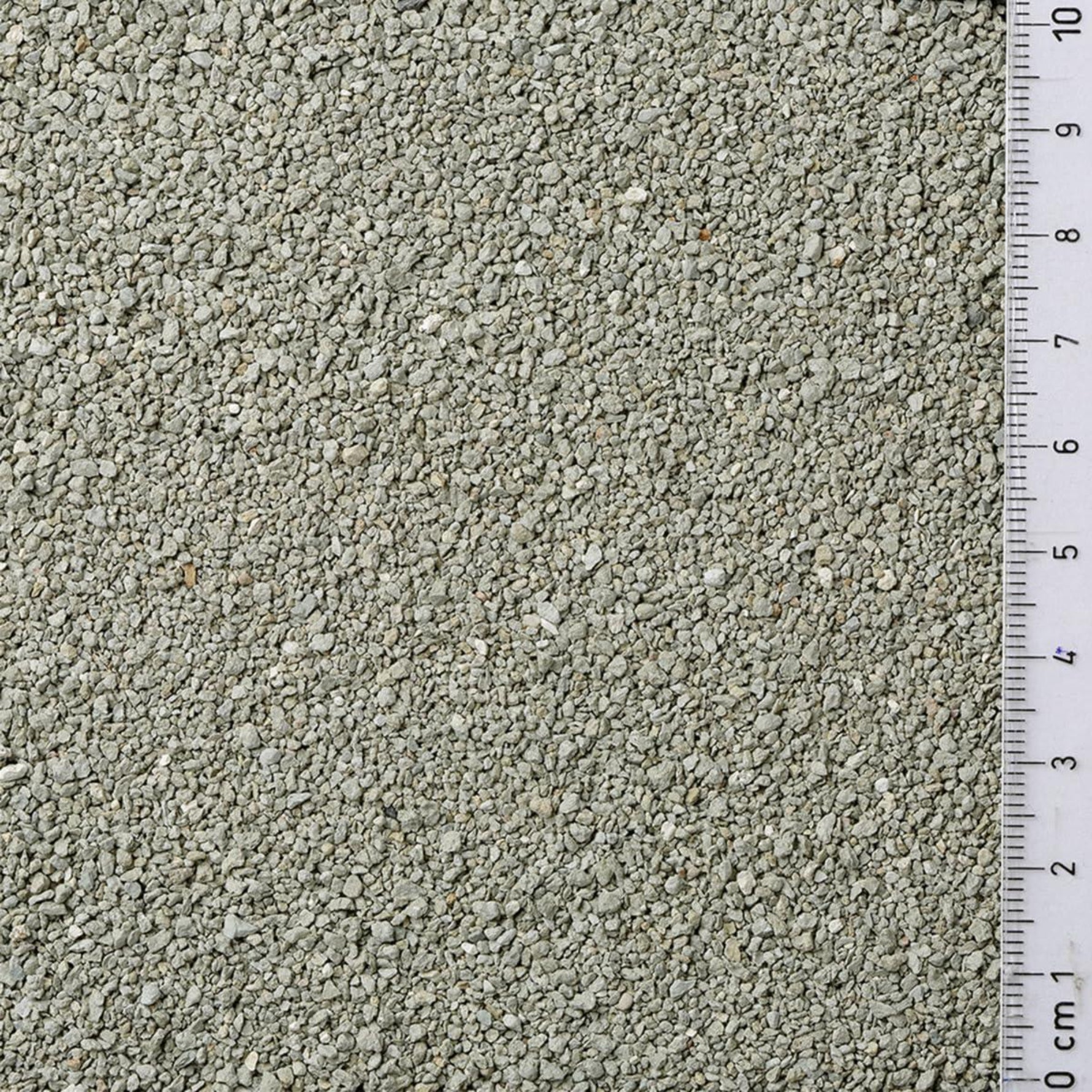 Close-up of light gray gravel with a ruler for scale